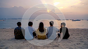 Group of Thai people, Asian friends, clanging bottles of beer together and celebrating on holiday in party at the beach or sea in