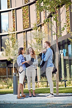 Group of three caucasian business people talking in front of a building. spontaneous chat