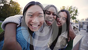 Group of three cheerful female friends looking at the camera hugging each other Happy girls outdoors