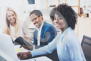 Group of three coworkers working together on business project in modern office.Young attractive african woman smiling, teamwork co