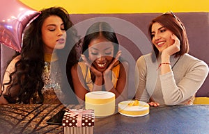 Group of three female friends at a cafe opening birthday presents and having fun