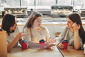 Group of three friends having fun a coffee together. Young women