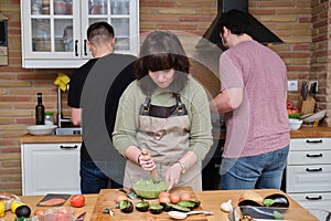 Group of three friends talking and cooking.