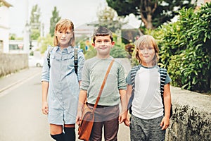 Group of three funny kids wearing backpacks walking back to school