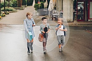 Group of three funny kids wearing backpacks walking back to school