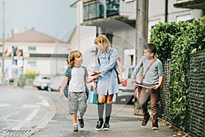 Group of three funny kids wearing backpacks walking back to school