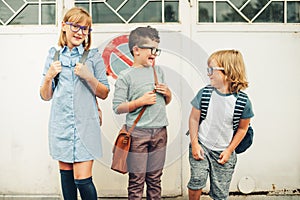 Group of three funny kids wearing backpacks walking back to school