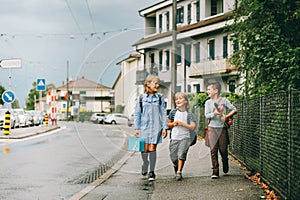 Group of three funny kids wearing backpacks walking back to school