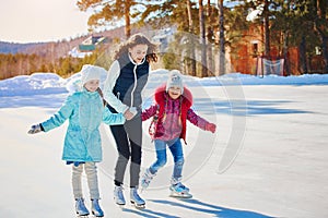 A group of three girls on a winter skating rink. Roll and laugh. Skating rink in nature.