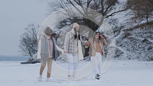 Group of three happy friends having fun and playing together in winter park.