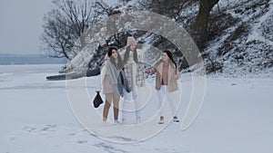 Group of three happy women having fun and playing with snow in winter park.