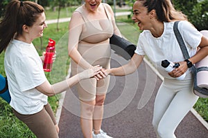 Group of three happy young adult girls 24-26 year old get together for yoga class in park outdoor.