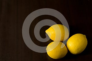Group of three lemons in corner on dark background