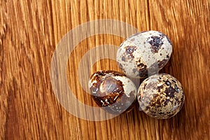 Group of three quail eggs on a wooden table, top view, close-up, selective focus, copy space.