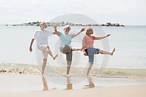 Group of three senior mature retired women on their 60s having fun enjoying together happy walking on the beach smiling playful