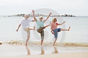 Group of three senior mature retired women on their 60s having fun enjoying together happy walking on the beach smiling playful