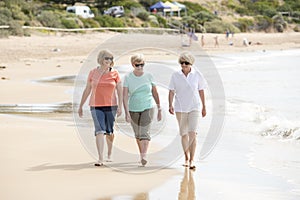 Group of three senior mature retired women on their 60s having fun enjoying together happy walking on the beach smiling playful