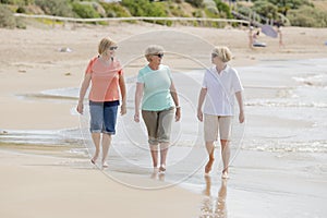 Group of three senior mature retired women on their 60s having fun enjoying together happy walking on the beach smiling playful