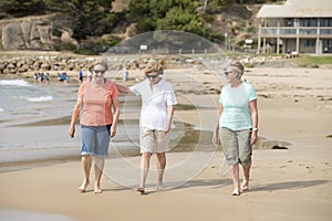 Group of three senior mature retired women on their 60s having fun enjoying together happy walking on the beach smiling playful