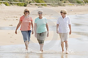 Group of three senior mature retired women on their 60s having fun enjoying together happy walking on the beach smiling playful