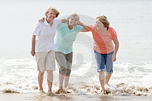 Group of three senior mature retired women on their 60s having fun enjoying together happy walking on the beach smiling playful