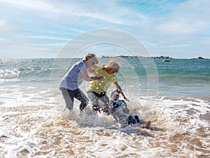 Group of three senior women laughing as falling down in the water on beach. Humor senior health