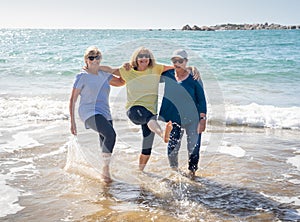 Group of three senior women walking having having fun on beach. Friendship and retirement lifestyle