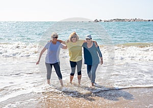 Group of three senior women walking having having fun on beach. Friendship and retirement lifestyle