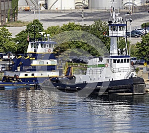 Group of three similar tugboats by a port pier in an industrial district along the Patapsco River near the downtown area of this