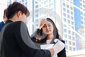 Group of three young Asian businesspeople socializing at modern city downtown with skyscraper building as blurred background.,