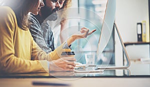 Grupo de tres joven companeros de trabajo en negocios común en soleado oficina. hombre escribiendo sobre el computadora teclado. una mujer muestra mano sobre el 