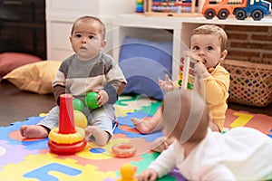 Group of toddlers playing with toys sitting on floor at kindergarten