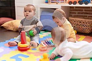 Group of toddlers playing with toys sitting on floor at kindergarten