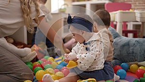 Group of toddlers playing with toys sitting on floor at kindergarten