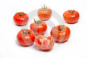 a group of tomatoes on a white background, with shadows. One tomato cut, studio photo, isolate, tomatoes washed