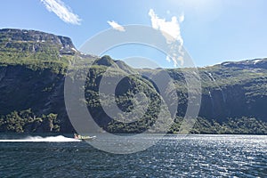 A group of tourist sitting in a jet boat on a sunny day in a river to enjoy mountain scenery