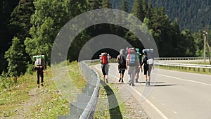 Group of tourists backpackers walking down the road, traveling