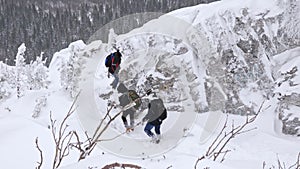 A group of tourists descends from the top of a snow-covered mountain.