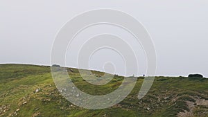 Group of Tourists with Hiking Backpacks Climbs the Mountain Range. Afar View