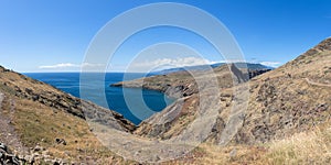 Group of tourists hiking in St. Lourenço Cape or Cabo de S. Lourenço, natural geological phenomenon, large cliffs over the ocean