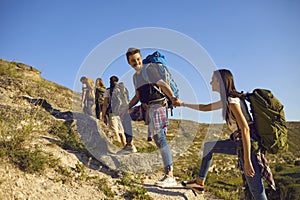 Group of tourists on hiking trip in mountains. Team of active young people with backpacks mountaineering outdoors