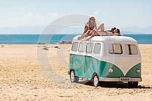 Group of tourists relaxing on top of hippie bus on beach