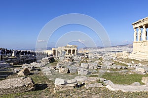 Group of tourists on the ruins of the Acropolis, view of Erechtheion with caryatids and gateway Propylaia, Athens, Greece