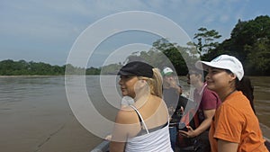 Group of tourists sailing in a wooden boat on the Aguarico river on a sunny morning