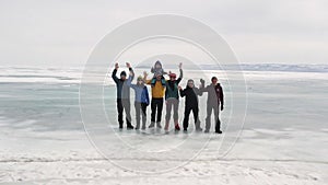 A group of tourists travels along the ice of the frozen Lake Baikal. Clip. Aerial view of happy people waving to the