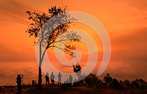 A group of tourists are watching the sunset with sea of fog at Nok aen Cliff in Phu Kradueng National Park.