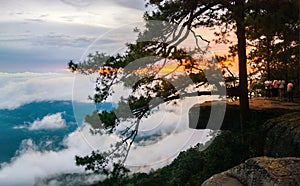 A group of tourists are watching the sunset with white clouds at Lomsak Cliff in Phu Kradueng National Park.