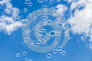 A group of transparent rainbow soap bubbles on the blue sky with white clouds background