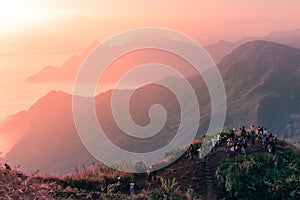 Group of traveler standing on top of the mountain to see and capture the sunrise scene.