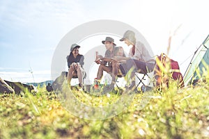 Group of travelers camping and doing picnic in meadow field foreground. Mountain and lake background. People and lifestyles